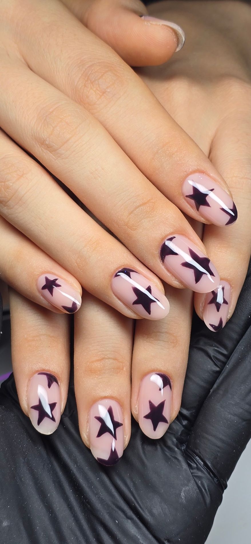 Uñas ovaladas nude con estrellas en ciruela oscuro