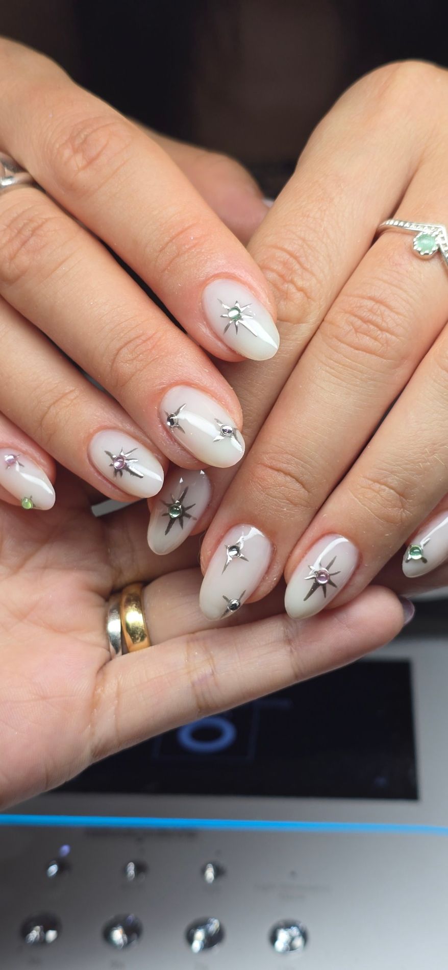 Uñas lechosas con estrellas plateadas y piedras de colores