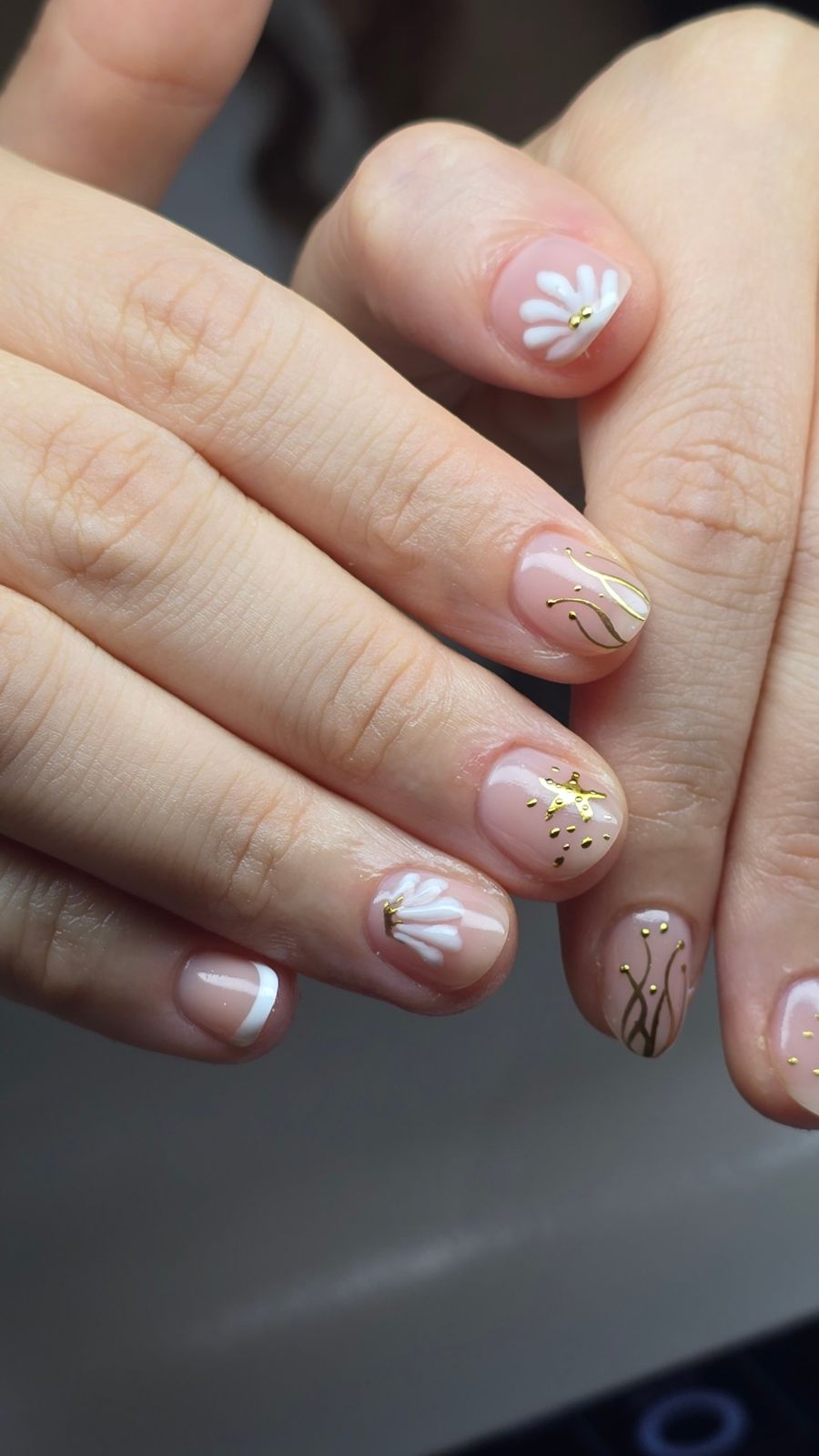 Uñas cortas nude con flores blancas y detalles en dorado