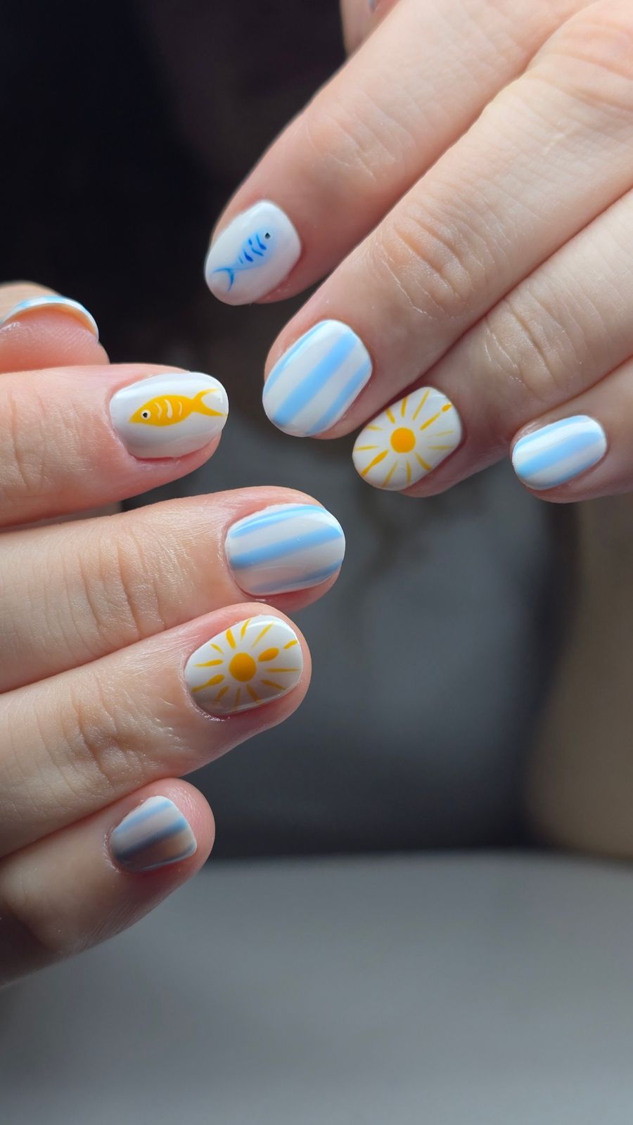 Uñas cortas blancas con rayas azules, sol y pez